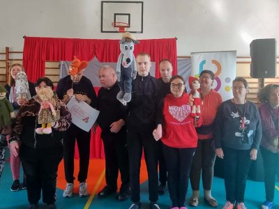 Widzowie pozują razem do wspólnego zdjęcia. Część z nich z entuzjazmem prezentuje maskotki, które zostały użyte podczas przedstawienia