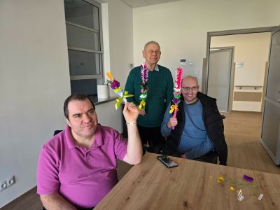 Trzech mężczyzn pozuje do zdjęcia. Każdy z nich trzyma w dłoni własnoręcznie stworzoną palmę wielkanocną